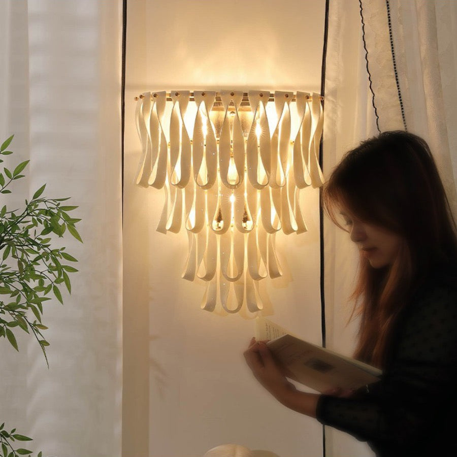 Warm lit ivory ceramic ribbon wall sconce in a room